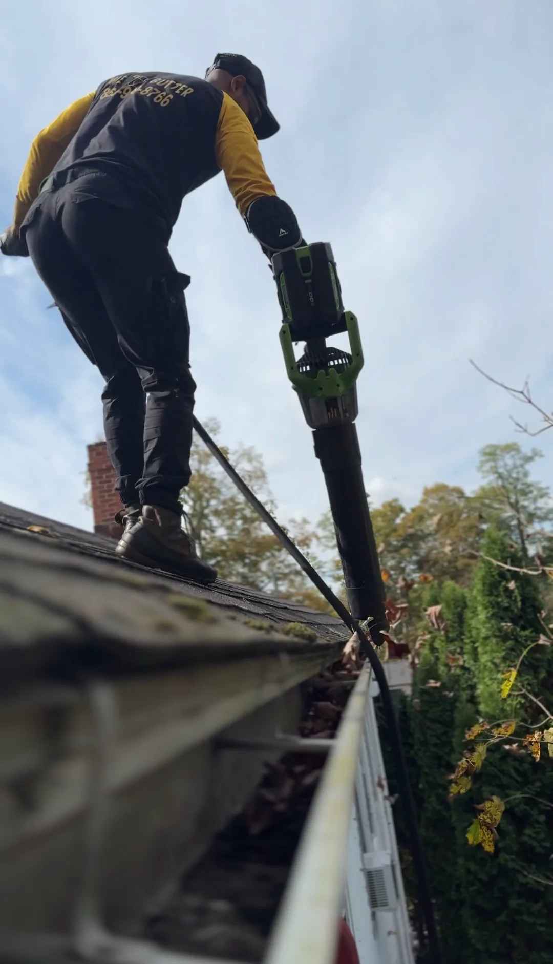 We Gutter technician cleaning gutters with leaf blower on a Connecticut roof — professional gutter cleaning in Waterbury CT